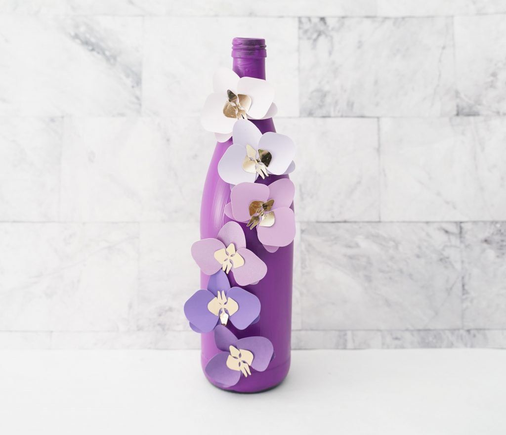 Bottle painted purple with cut out flowers attached to it for a 3D effect