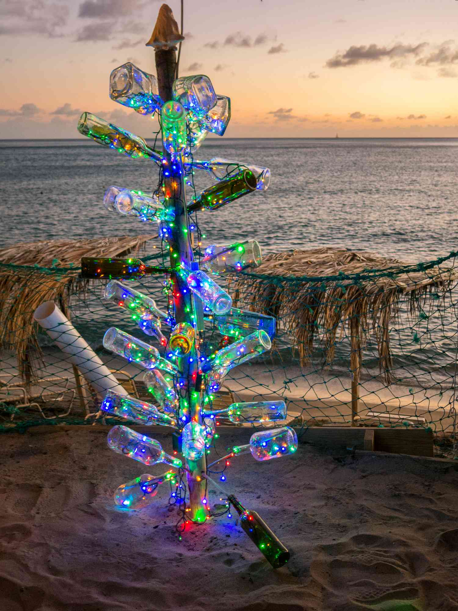 Christmas tree on the beach made out of bottles with lights inside them 