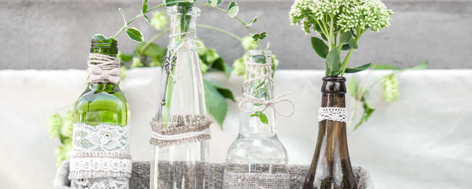 Centerpiece made up of bottles wrapped in lace and twine and filled with greenery