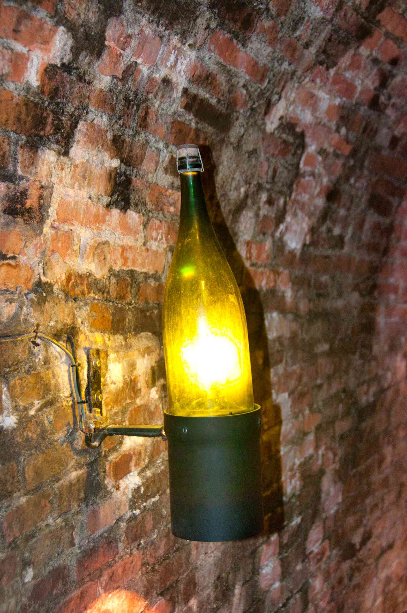 Wine bottle used as a sconce on a brick wall