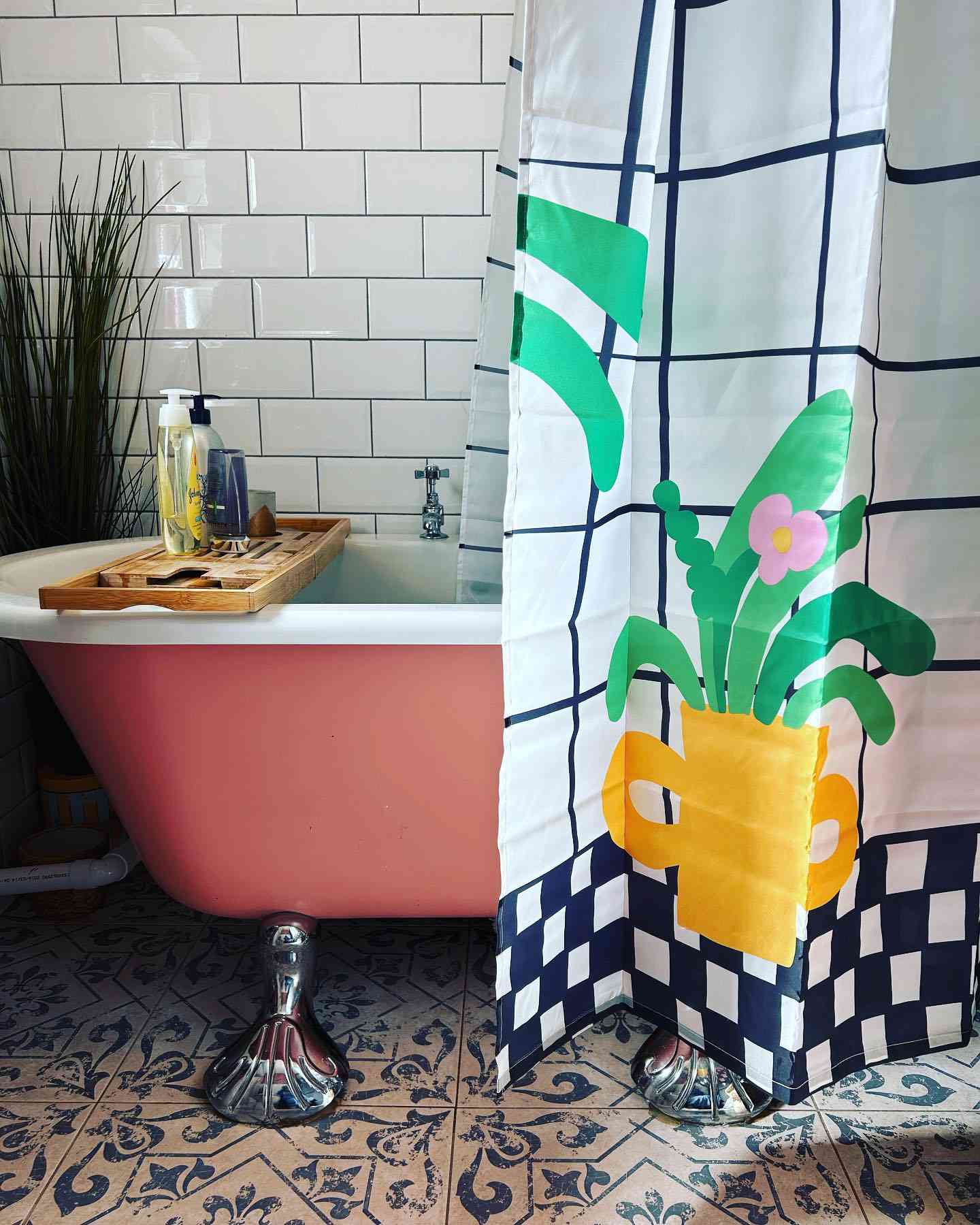 Badrum med rosa klövfotsbadkar och växtdraperi
