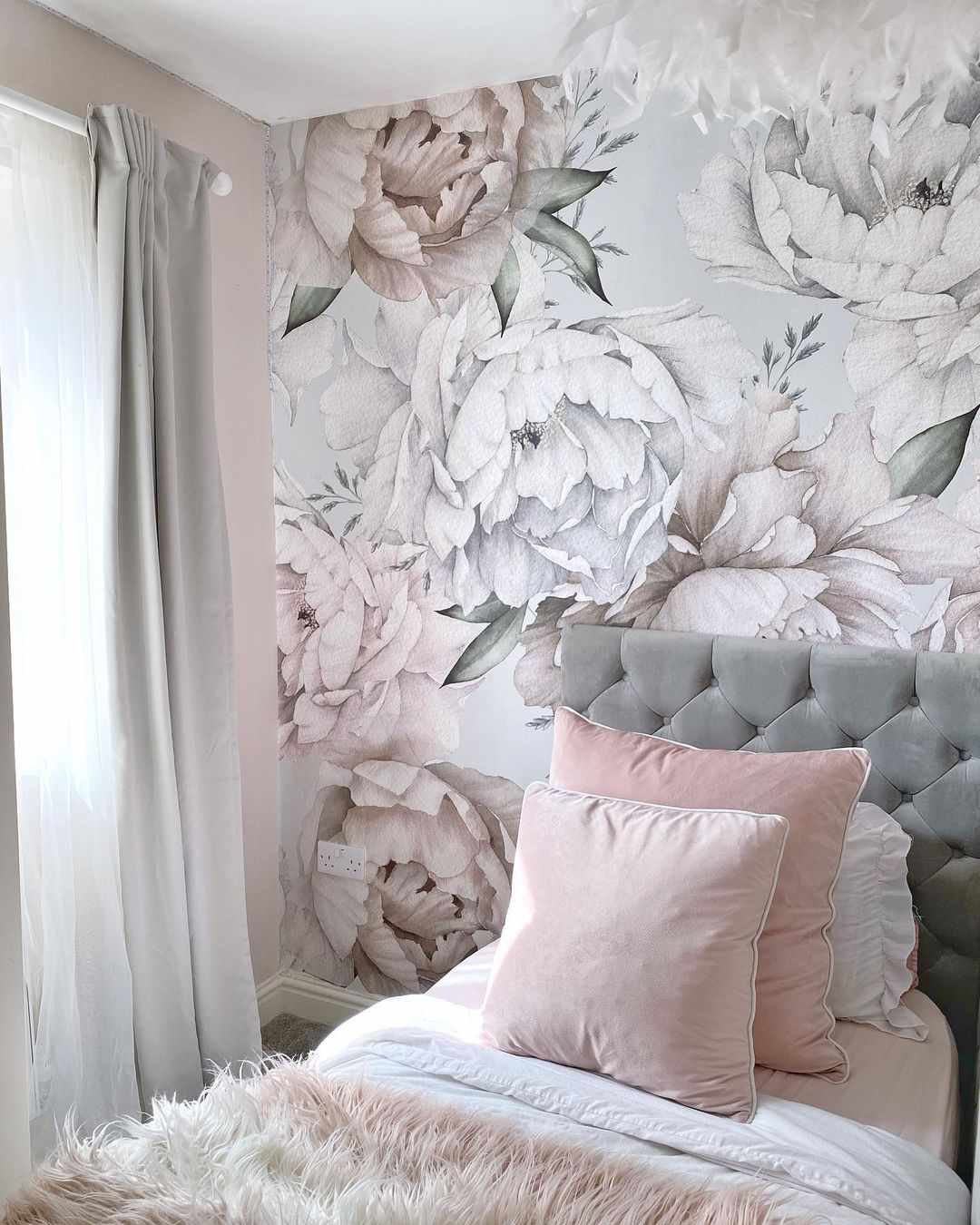 Storblommig tapet i dämpade grå och rosa toner i en tonårsflickas sovrum.