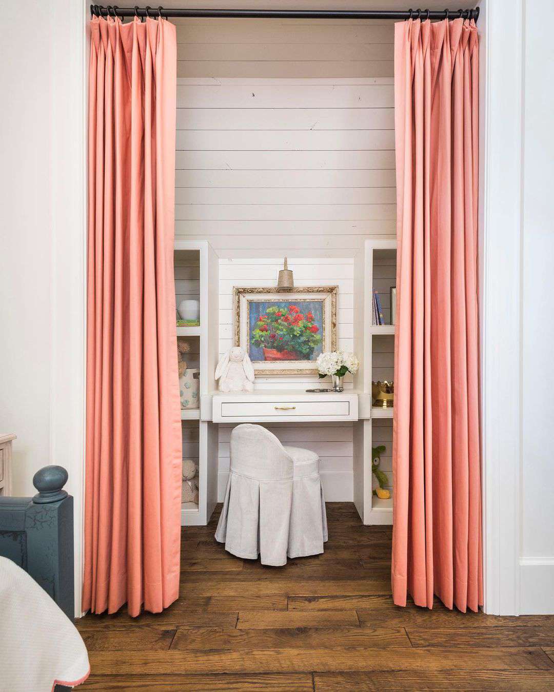 En privat läxläsningshörna i en tonårsflickas sovrum med rosa gardiner från golv till tak och en shiplap-vägg.