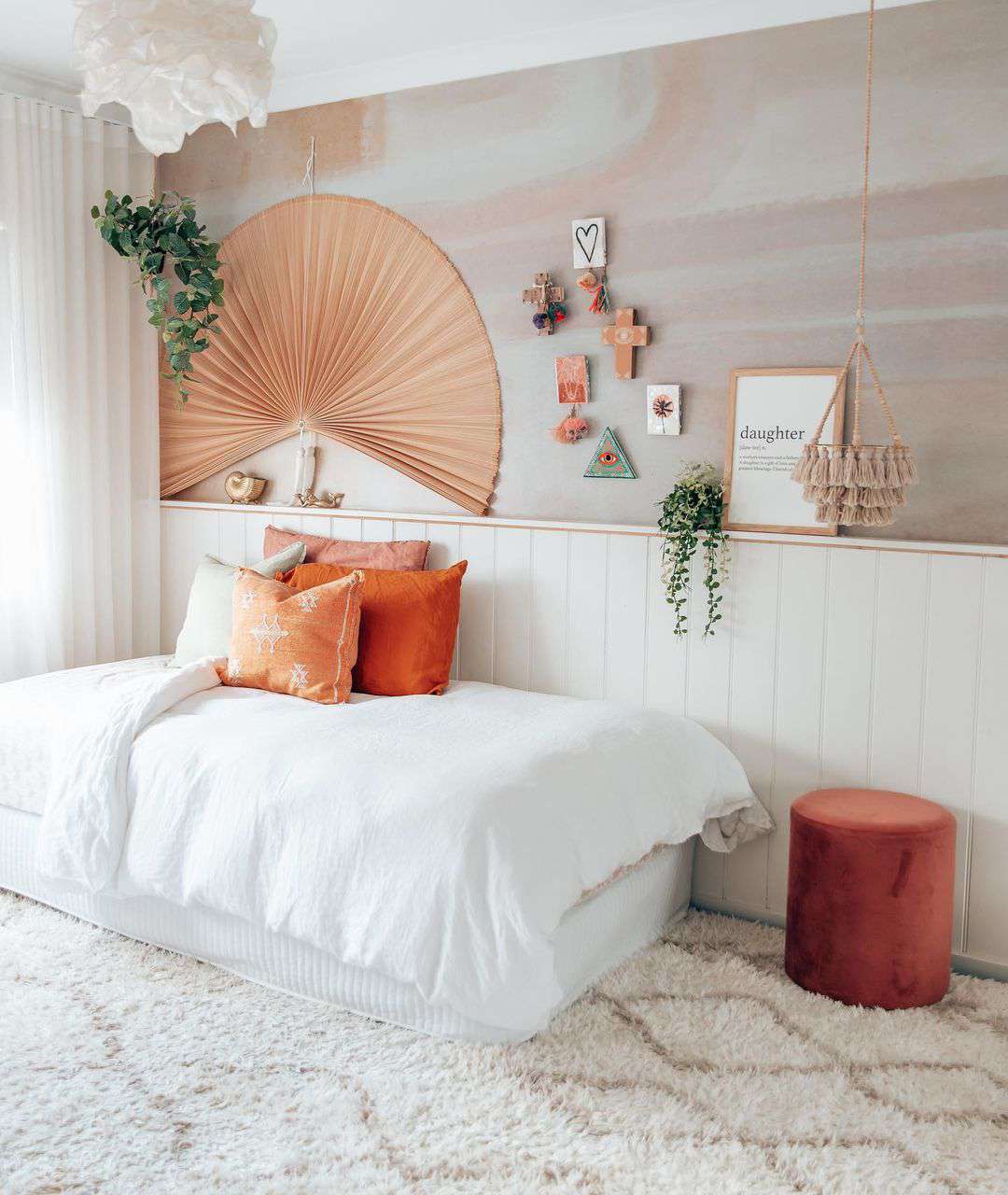 Ett boho-inspirerat tonårsrum med akvarellväggar, en stor pappersfläkt, en dagbädd och en hängande tofs-planter.