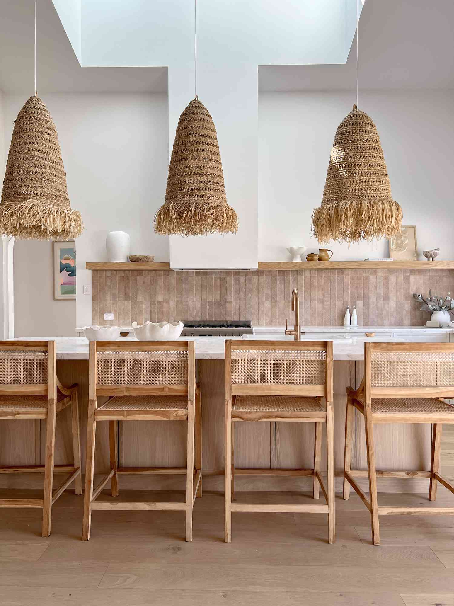Ett mestadels rosa kök har sandiga detaljer som en terrakotta kaklad backsplash