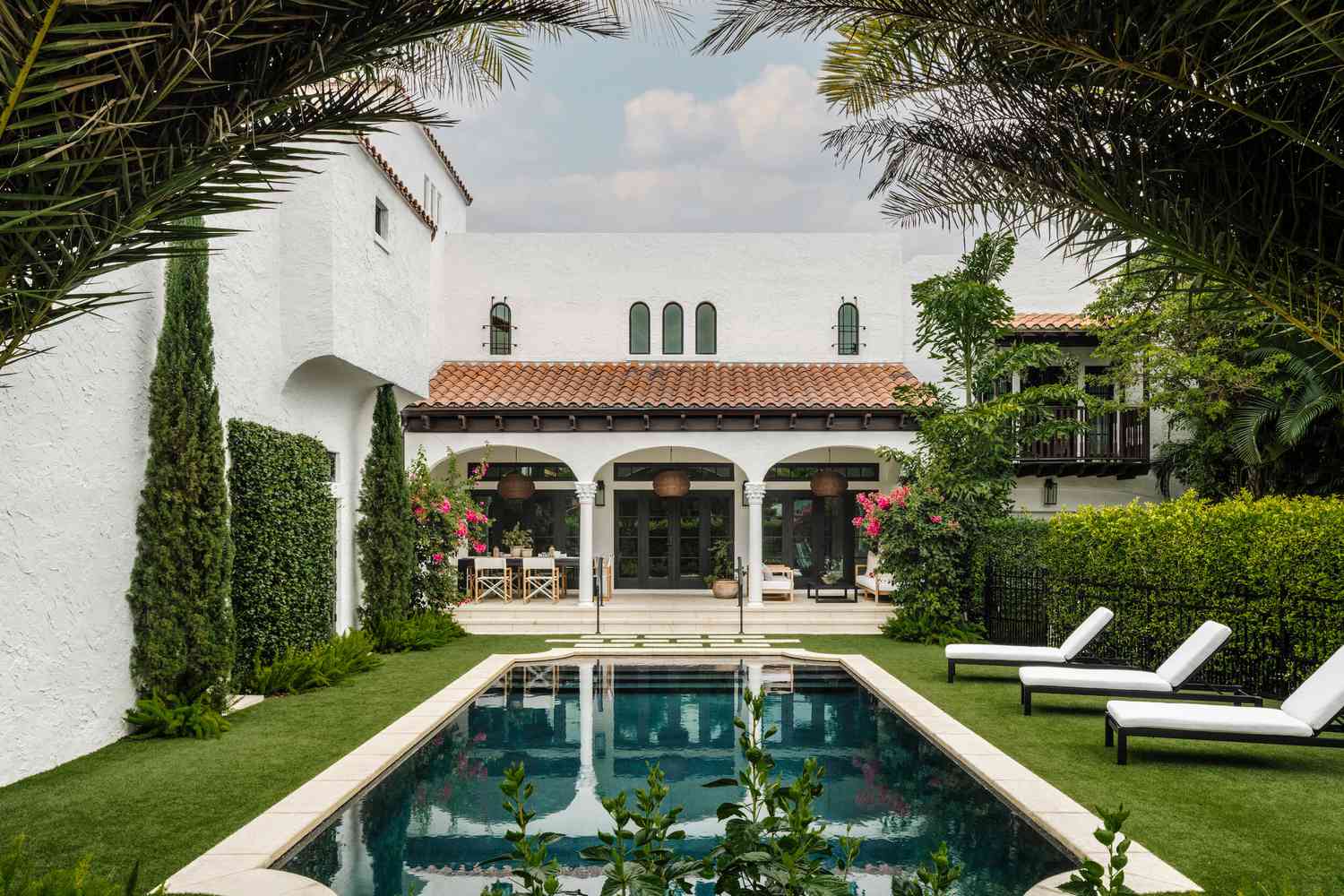 Bakgård med pool och vit husfasad med svarta lister och välvda detaljer