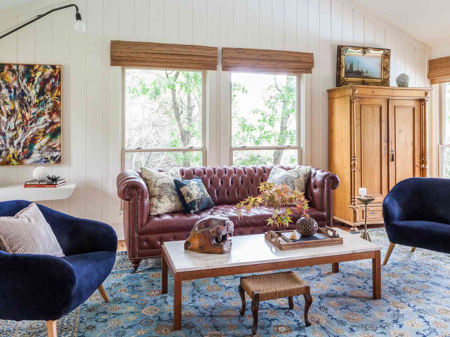 Ett vardagsrum med en röd Chesterfield-soffa toppad med blå och benvita tryckta kuddar