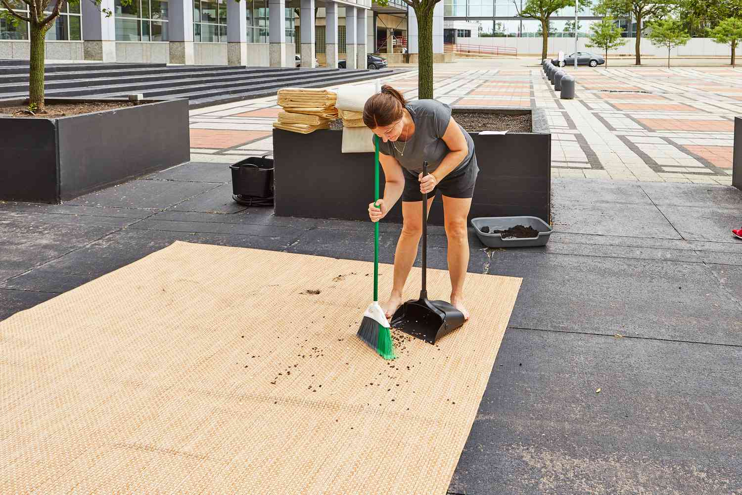 Person som rengör spill på Safavieh Courtyard Beige and Brown Solid Indoor/Outdoor Area Rug med en kvast och dammvippa 