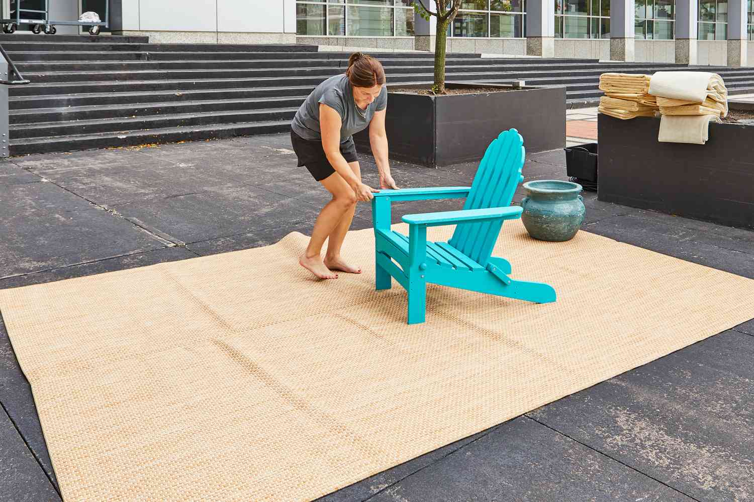 Person som placerar en Adirondack-stol på Safavieh Courtyard Beige and Brown Solid Indoor/Outdoor Area Rug