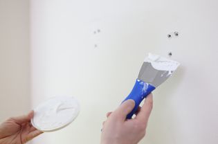 Person som reparerar hål i gips