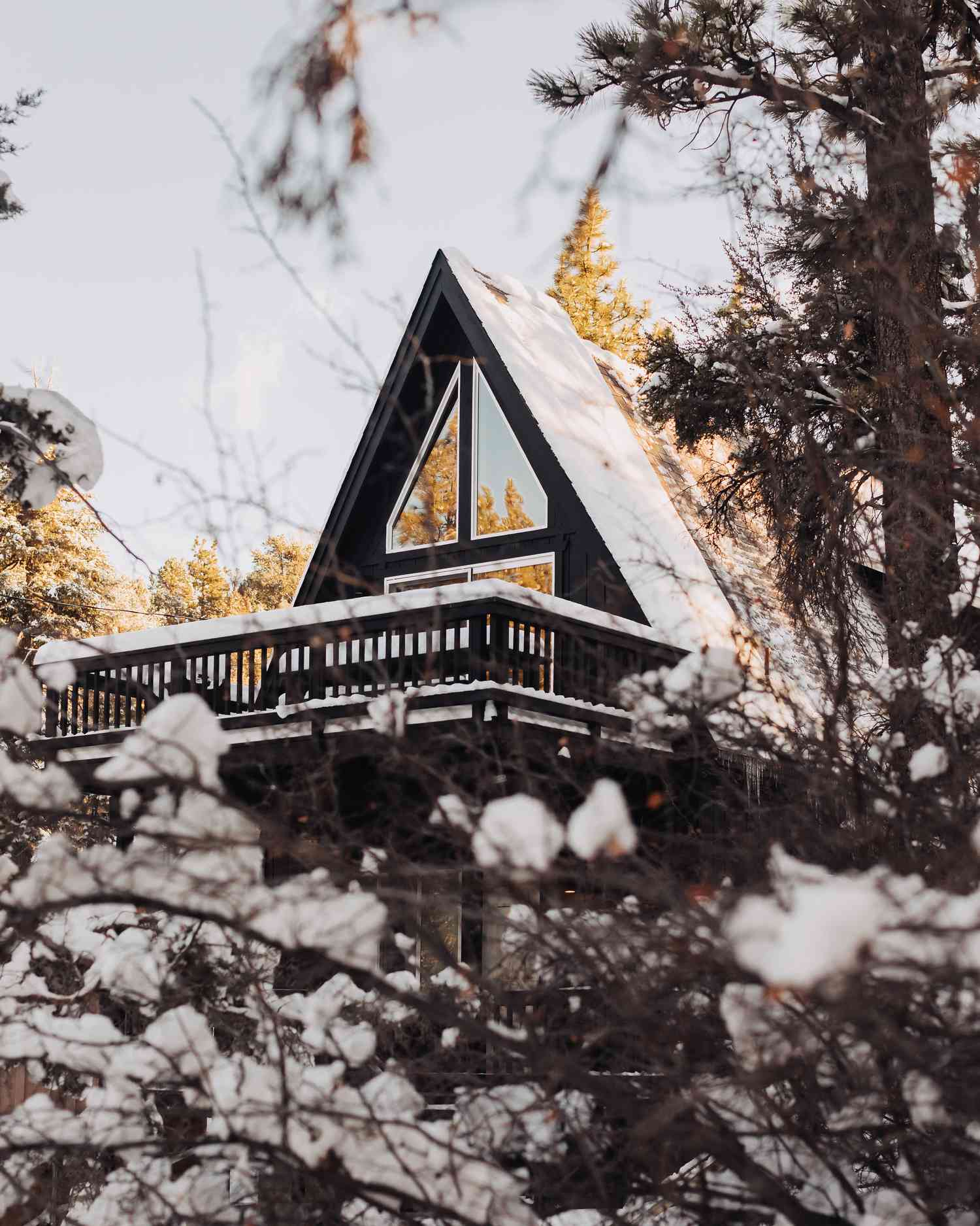 En svart stuga med ramverk i en snöig skog på landsbygden