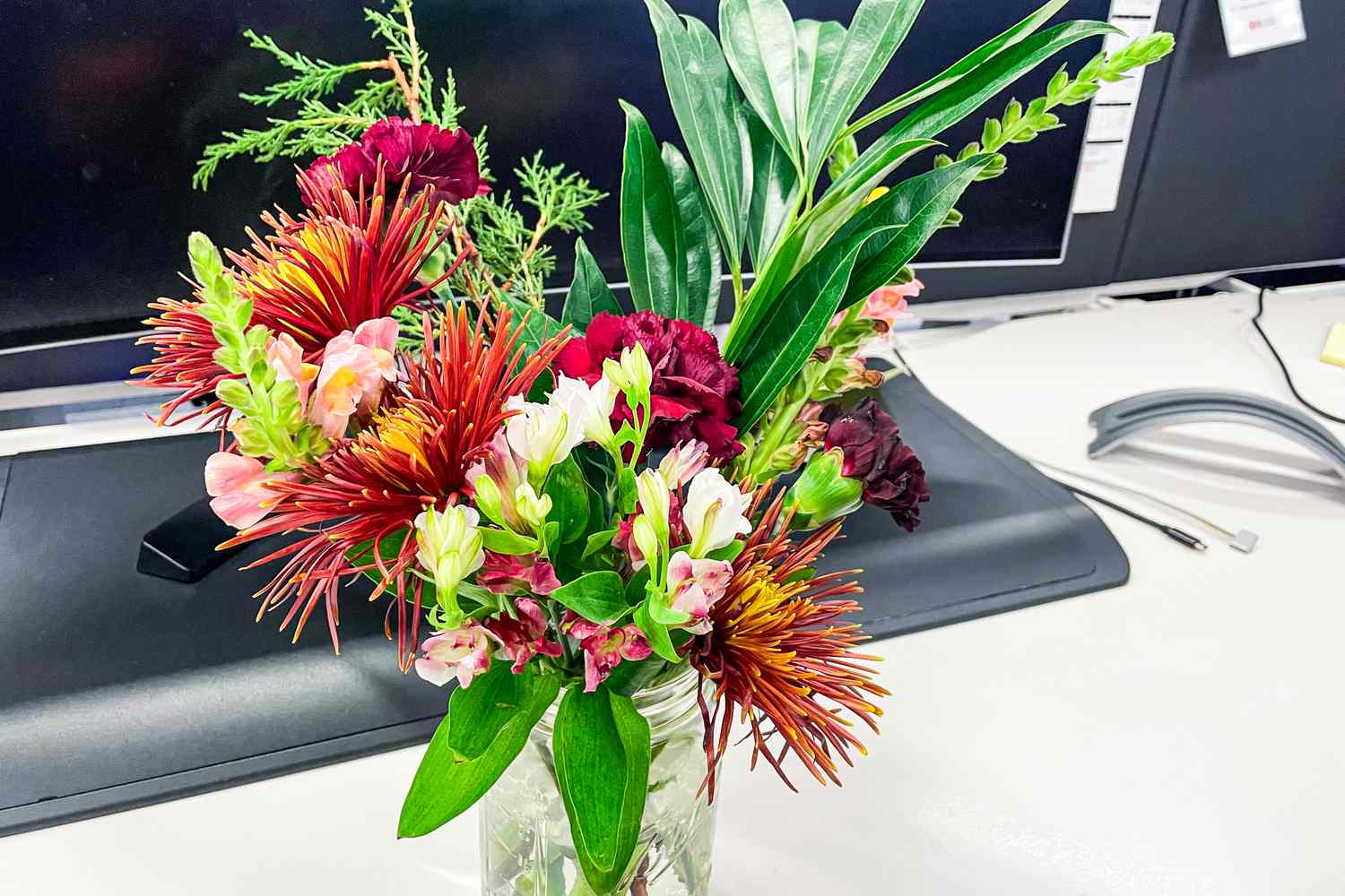 Närbild av blommor från Enjoy Flowers-boxen i en vas på ett skrivbord