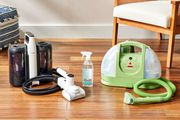 Ett sortiment av klädselrengöringsmedel som vi rekommenderar, inklusive Bissell Little Green Original Carpet & Upholstery Cleaner, sida vid sida på ett trägolv
