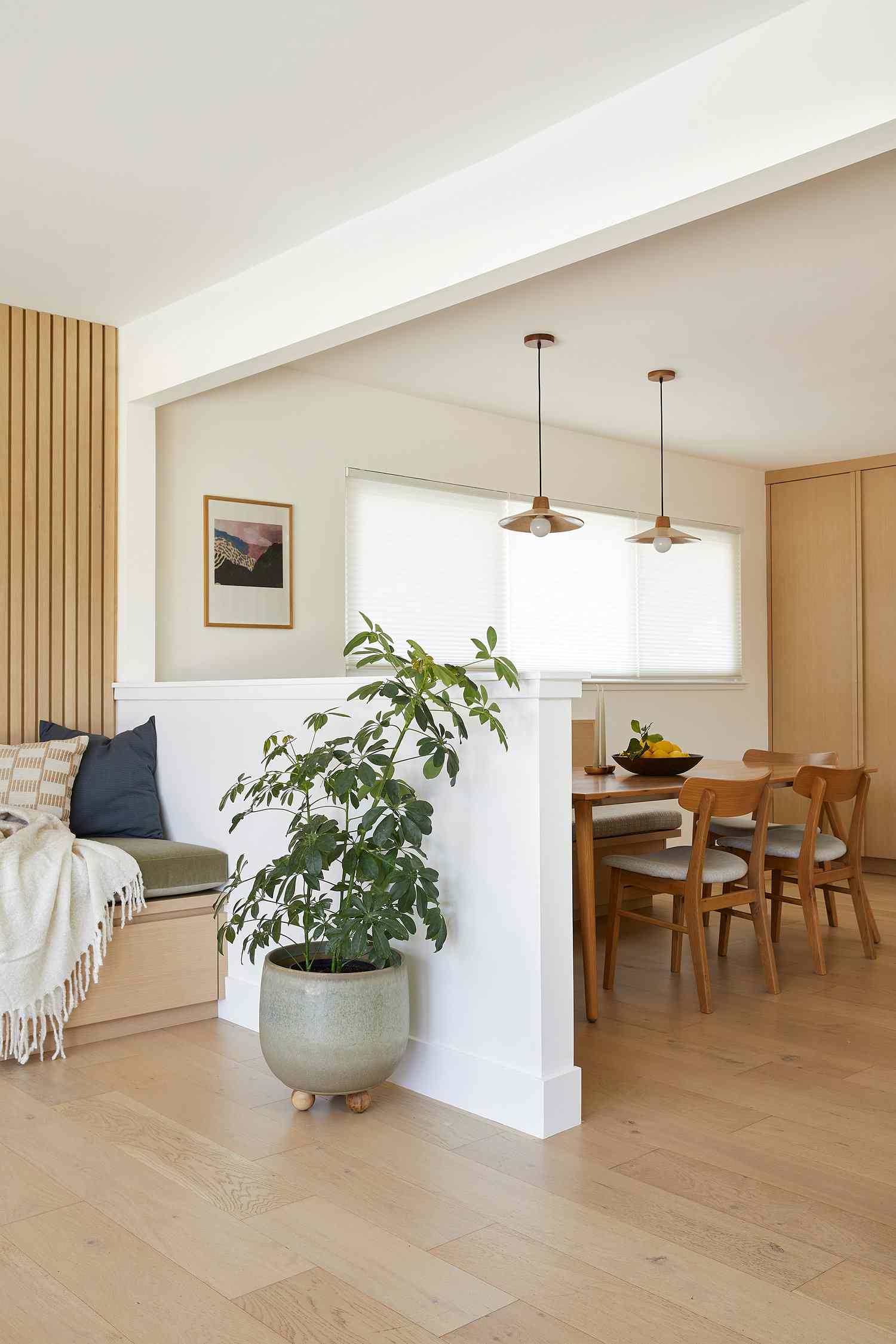 Japandi inspired living room with built-in sofa bunch and potted plant in a sage green ceramic planter