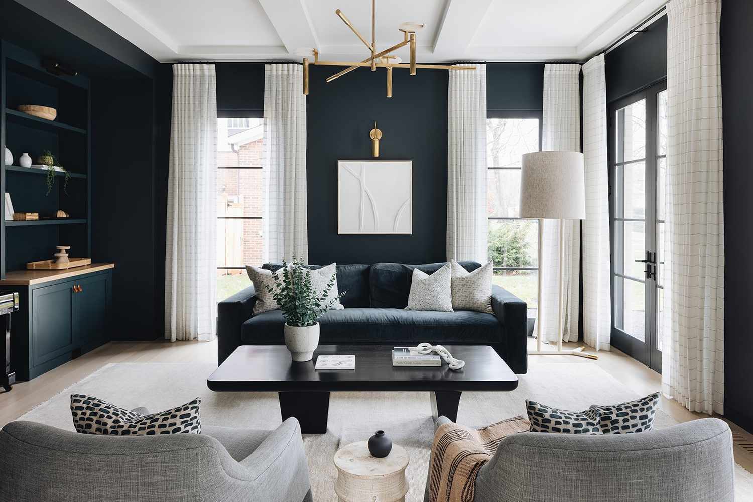 Dark navy painted living room with white drapes and brass lighting 